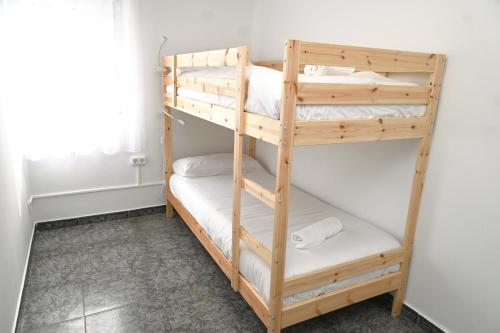 Ce lit superposé en bois se trouve dans un dortoir. dans l'établissement Homenfun Barcelona Bellvitge, à L'Hospitalet de Llobregat