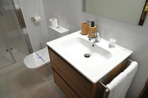La salle de bains est pourvue d'un lavabo blanc et de toilettes. dans l'établissement Homenfun Barcelona Bellvitge, à L'Hospitalet de Llobregat
