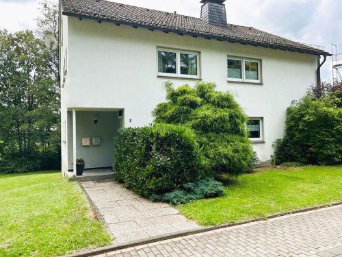 uma casa branca com uma porta e alguns arbustos em Ferienwohnung Sauerland an der Ruhr em Olsberg