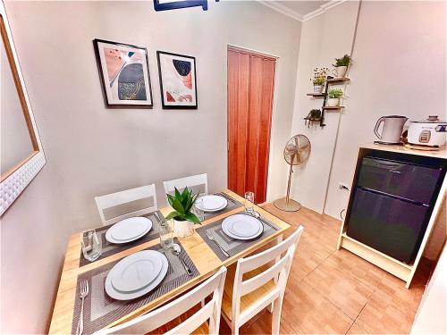 un comedor con una mesa con platos blancos. en Cozy BNB - Unit E, en Batangas