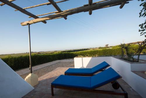 a blue bench sitting on a patio with the ocean in the background at Herdade Do Touril in Zambujeira do Mar