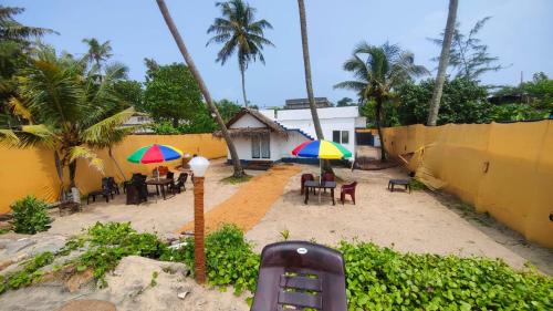 a patio with tables and chairs with umbrellas at Tripsea Beach Villa in Alleppey