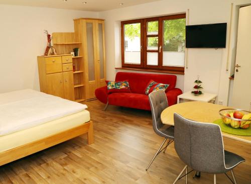 a room with a bed and a table and a red couch at Appartement Schwarzwaldstüble in Oberharmersbach