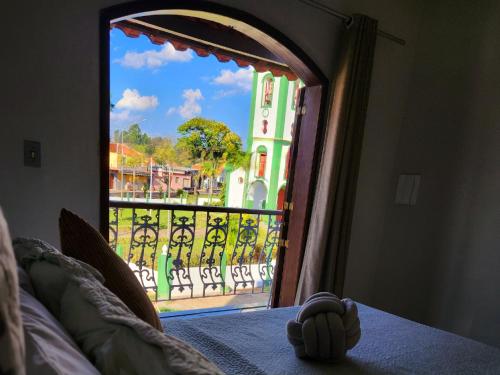 a bedroom with a window looking out onto a balcony at PousaDinháChica Hospedagem perto de Tiradentes Minas Gerais in São João del Rei