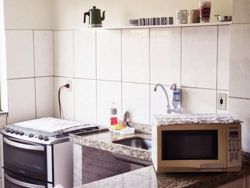 a kitchen with a sink and a microwave at PousaDinháChica Hospedagem perto de Tiradentes Minas Gerais in São João del Rei