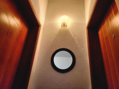 a bathroom with a mirror and a light on a wall at PousaDinháChica Hospedagem perto de Tiradentes Minas Gerais in São João del Rei