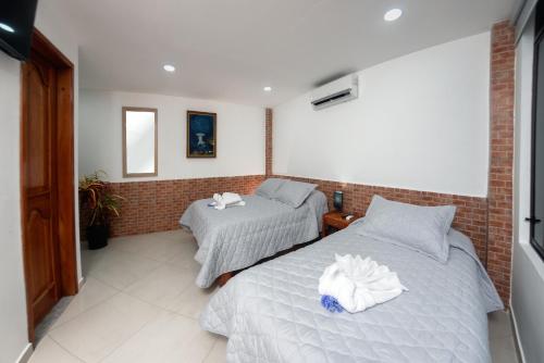 1 dormitorio con 2 camas y pared de ladrillo en Fernandina Hotel & Spa, en Puerto Ayora