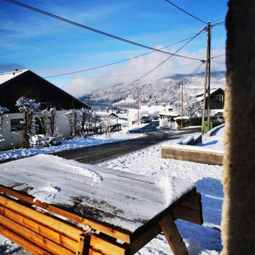 un banc en bois recouvert de neige dans une ville dans l'établissement L'Écrivain, Vue lac, proche pistes de ski, à Gérardmer