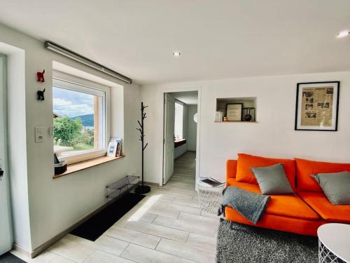 - un canapé orange dans le salon avec une fenêtre dans l'établissement L'Écrivain, Vue lac, proche pistes de ski, à Gérardmer