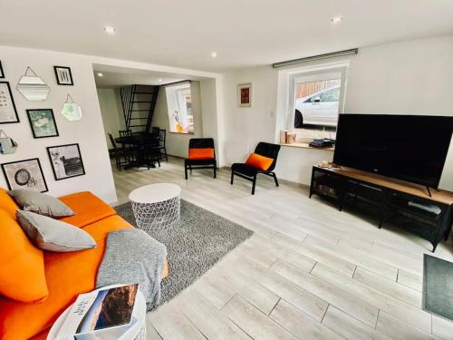 Il comprend un salon doté d'un canapé orange et d'une télévision à écran plat. dans l'établissement L'Écrivain, Vue lac, proche pistes de ski, à Gérardmer