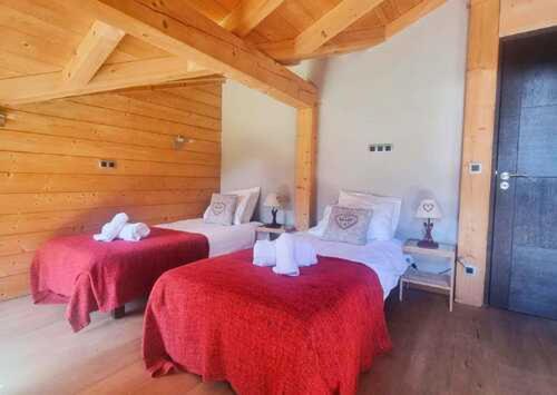 a bedroom with two beds with red sheets and white towels at Les Drus - Luxury Chalet for 8 in Chamonix-Mont-Blanc