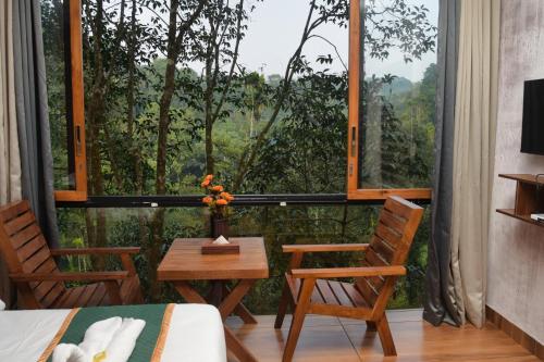a room with a bed and chairs and a large window at TREE6 WAYANAD in Vythiri