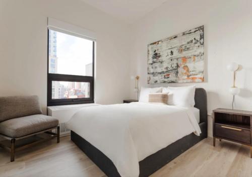 um quarto branco com uma cama grande e uma cadeira em Amazing 4 Bedroom Apartment In Chambers Street em Nova York
