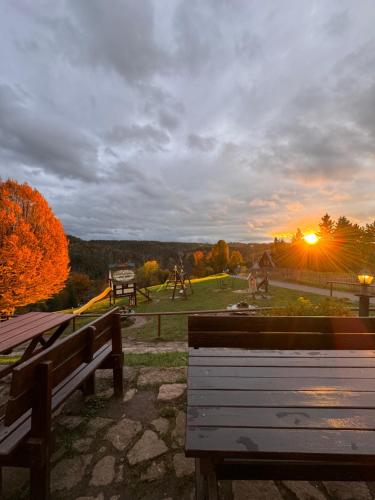 ein Park mit Bänken und der Sonnenuntergang im Hintergrund in der Unterkunft Resort Mezná in Hřensko
