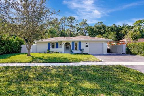 a white house with a tree and a driveway at Bungalow Close to Naples Beaches in Naples