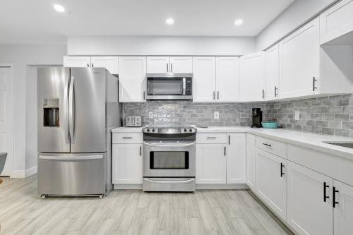a kitchen with white cabinets and stainless steel appliances at Bungalow Close to Naples Beaches in Naples