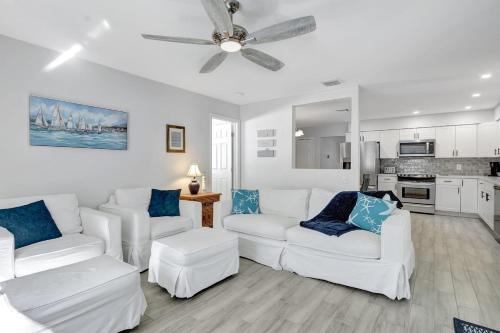 a living room with white furniture and a ceiling fan at Bungalow Close to Naples Beaches in Naples