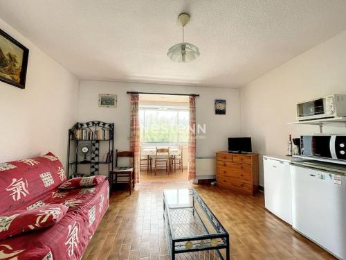 un salon avec un canapé rouge et une cuisine dans l'établissement 3086-Appartement 2pièces bien situé, à Argelès-sur-Mer