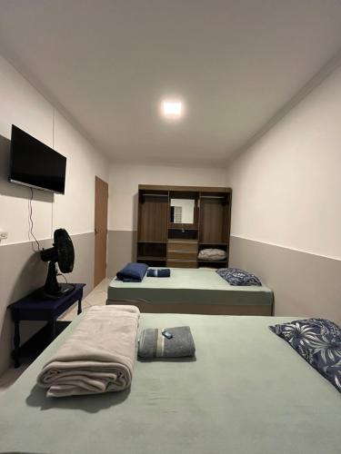 a room with two beds and a flat screen tv at Toca do Tatu in Itu