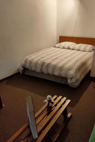 un ours en peluche assis sur un banc à côté d'un lit dans l'établissement Le Seignus: superbe studio avec vue sur les pistes, à Allos