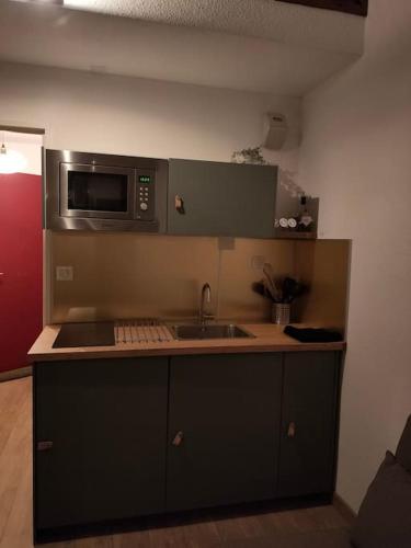 une cuisine avec un évier et un micro-ondes dans l'établissement Le Seignus: superbe studio avec vue sur les pistes, à Allos