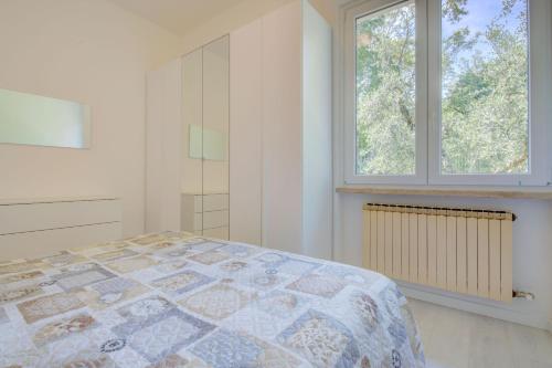a white bedroom with a bed and two windows at Appartamento Rupestre in Manerba del Garda