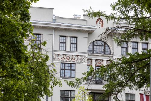 um edifício branco com janelas e árvores negras em Smart park view studio in heart of Riga 5 min to Old Town em Riga