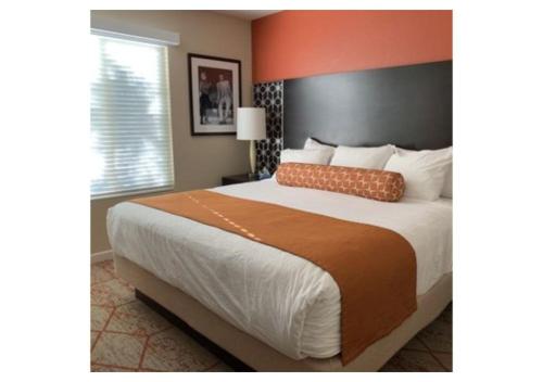 a bedroom with a large bed with an orange headboard at Escape to Tropicana, a Tranquil Condo Oasis Near the LV Strip - Special Offer Now! in Las Vegas