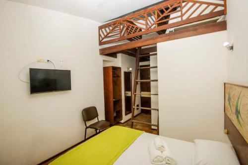 a bedroom with a bed and a tv on a wall at Pousada Caravelas de Pinzón in Cabo de Santo Agostinho