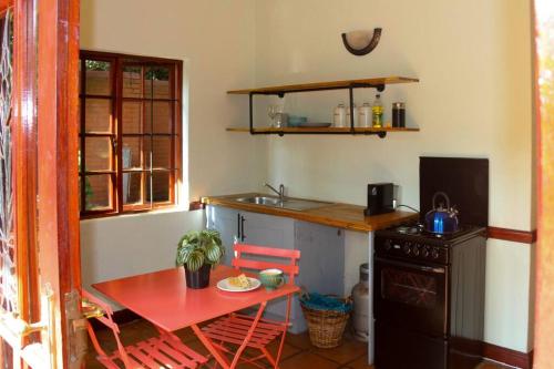 - une cuisine avec une table, une petite table et une cuisinière dans l'établissement Cosy Bachelors, 2 min walk to Melville 7th, à Johannesbourg