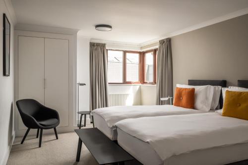 um quarto de hotel com duas camas e uma cadeira em Monarch House - Serviced Apartments - Kensington em Londres