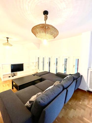 a living room with a large couch and a chandelier at Appartamento nel verde fronte ospedale San Pietro, Sant'Andrea in Rome