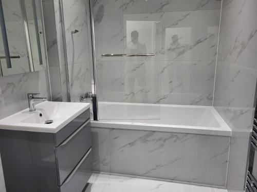 a white bathroom with a tub and a sink at 1 Bed Flat, Fibre Broadband, New, Washer Dryer, 10 mins from city centre in Dartford