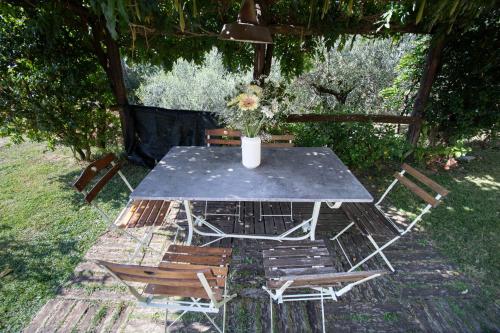 a table with chairs and a vase with flowers on it at Villa Iris with Swimming Pool in Capannori