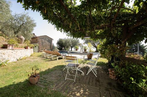 a patio with a table and chairs under a tree at Villa Iris with Swimming Pool in Capannori
