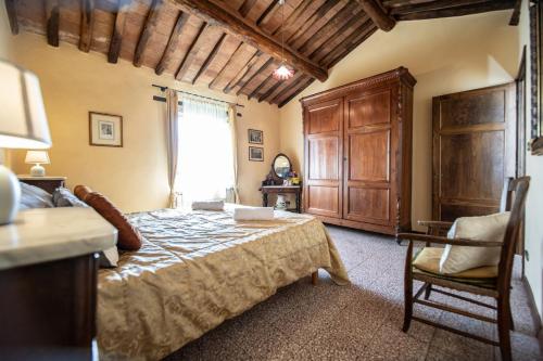 a bedroom with a bed and a chair and a window at Villa Iris with Swimming Pool in Capannori