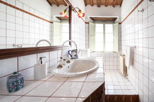 Baño de azulejos blancos con lavabo y espejo en Villa Iris with Swimming Pool, en Capannori
