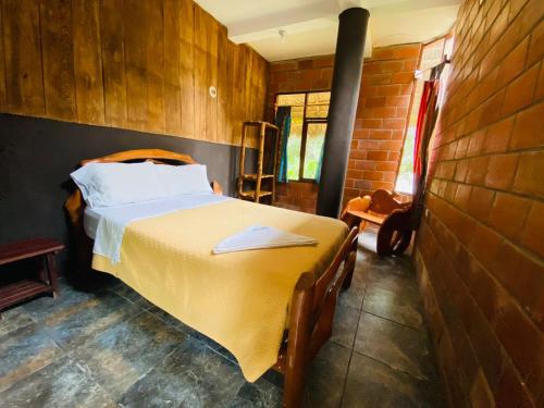 1 dormitorio con cama y pared de ladrillo en River Spot Lodge home of the chocolate & coffe History center&river tours, en Tena