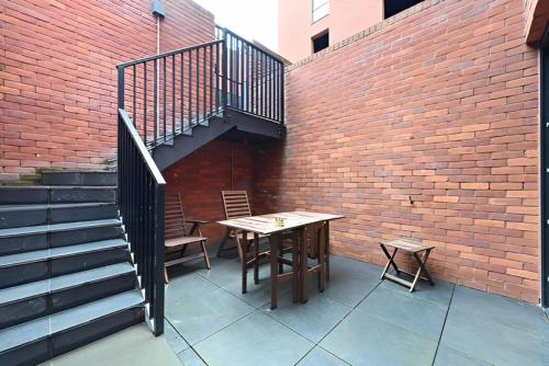 a patio with a wooden table and chairs next to a brick wall at Richardson Deluxe Apartments in London