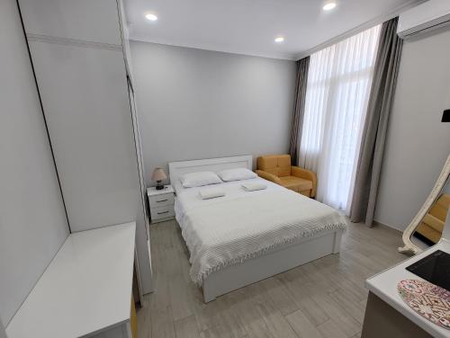 a white bedroom with a bed and a chair at Апартаменты с видом на горы in Makhinjauri