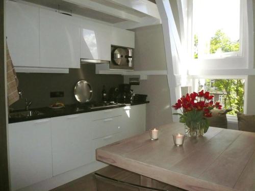 a kitchen with white cabinets and a table with flowers at Park Mansion Hotel in Amsterdam