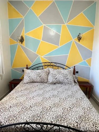 a bedroom with a bed with a geometric wall at Maison à harhoura prêts de la plage in Rabat