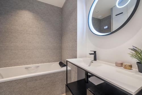 a bathroom with a sink and a tub and a mirror at Atelier in Paris