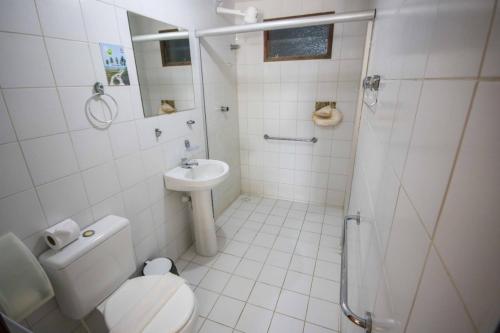 La salle de bains blanche est pourvue de toilettes et d'un lavabo. dans l'établissement Pousada Caravelas de Pinzón, à Cabo de Santo Agostinho