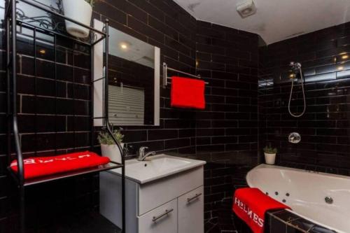 a black tiled bathroom with a white sink and a tub at 2Bedroom Suite Shenkin Hotel in Tel Aviv