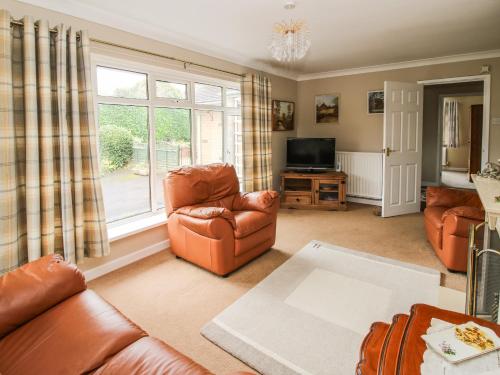 a living room with leather furniture and a window at The Highlands in Church Stretton