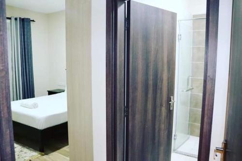 ein Bad mit einer Dusche und ein Schlafzimmer mit einem Bett in der Unterkunft Yohana Residences in Nairobi