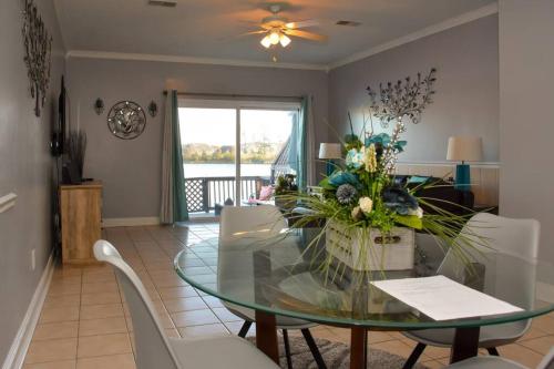 チャールストンにあるScenic Carolina Waterfront Rentals - Arcoのガラスのテーブルと白い椅子のあるダイニングルーム