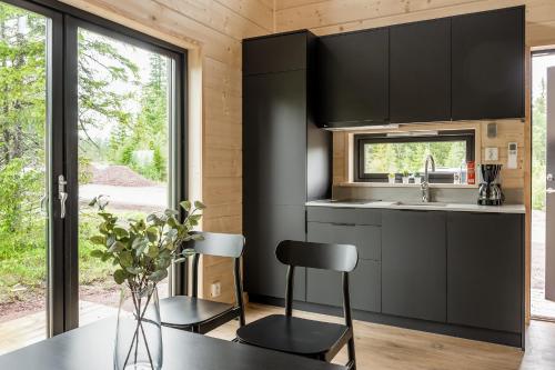 a kitchen with black cabinets and a table and chairs at Liten stuga nära Lindvallen in Sälen