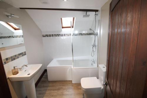 a bathroom with a tub and a toilet and a sink at The Hayloft, Broughton Beck, near Ulverston in Spark Bridge